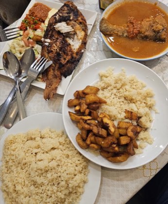 Poisson braisé entier, attiéké, alloco et bol de sauce, servis à table