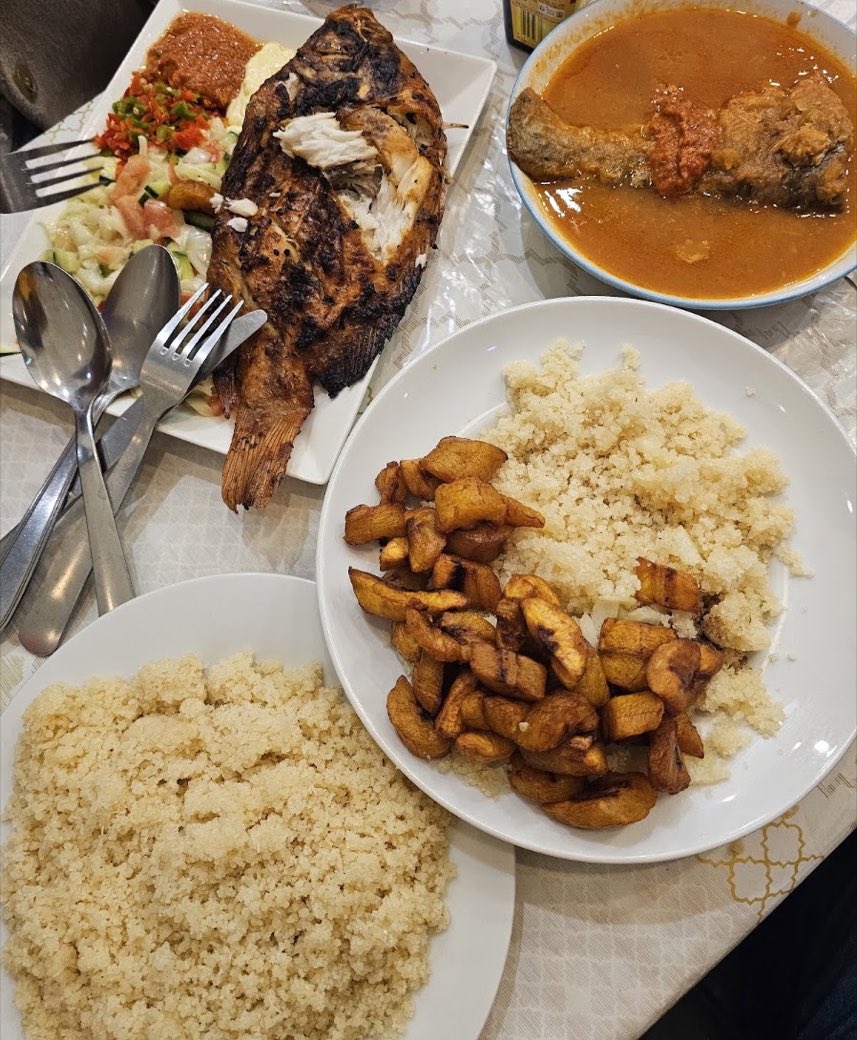 Poisson braisé entier, attiéké, alloco et bol de sauce, servis à table